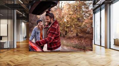 Young happy caucasian couple getting ready to go hiking in a forest or national park Wall mural