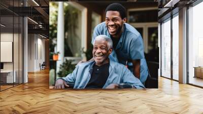 Young male caregiver pushing a senior man in his wheelchair in a nursing home smiling and laughing Wall mural