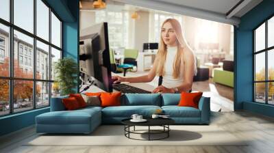 Young woman working a computer desk job Wall mural