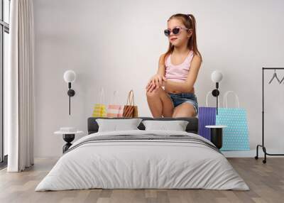 Cute little girl with shopping bags on a white background Wall mural