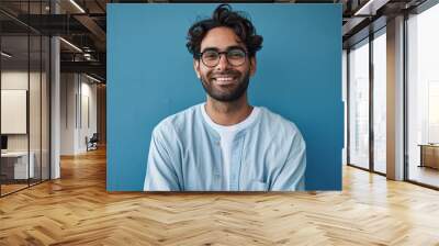 Smiling confident arab young man, male student, professional employee or programmer standing isolated on blue background. Happy handsome ethnic guy wearing shirt and glasses, Generative AI  Wall mural