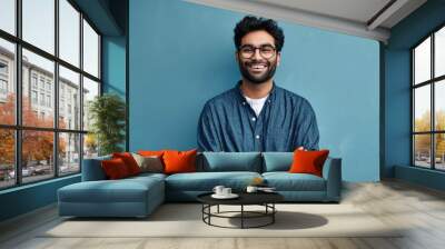 Smiling confident arab young man, male student, professional employee or programmer standing isolated on blue background. Happy handsome ethnic guy wearing shirt and glasses, Generative AI  Wall mural