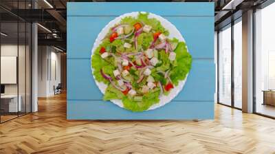 Salad of vegetables and lettuce and feta on a white plate. Blue wooden background. The concept of healthy eating. Wall mural