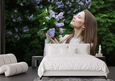 A 30-year-old woman enjoys the aroma of a bouquet of lilacs. Wall mural