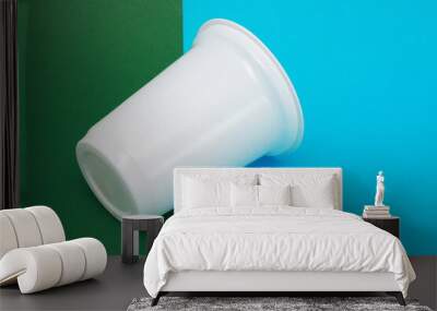 White plastic cup lying on two color background. Wall mural