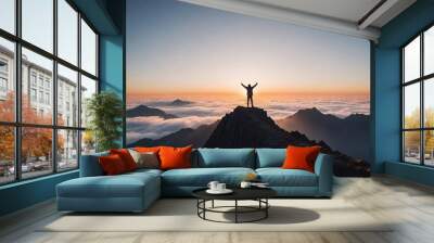 person standing on top of a mountain peak with arms raised, above the clouds during sunrise  Wall mural