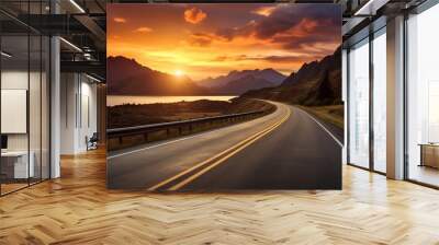 Scenic winding road at sunset with stunning mountain and lake views, offering a serene and picturesque travel experience. Wall mural