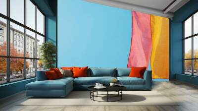 Colorful fabric pieces hang against a blue background, adding vibrancy and texture to any design or creative project. Wall mural