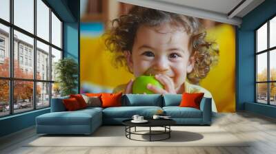 Adorable latin toddler smiling happy eating green apple looking to the camera over isolated yellow background : Generative AI Wall mural