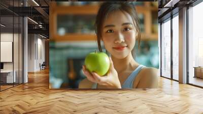 Asian attractive active woman pick up a green apple in kitchen at home Beautiful sport girl in sportswear holding a fruit enjoy eat healthy food for health after exercise and look at c : Generative AI Wall mural