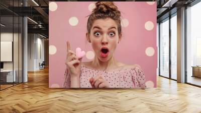 Beauty surprised Young fashion model Girl with Valentine Heart shaped cookie in hand Love Beautiful young woman pointing hand advertising gesture Valentines Day gift Pink polka dots ba : Generative AI Wall mural