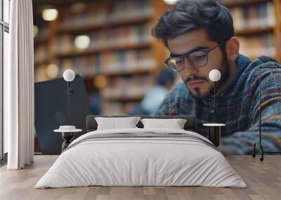 Latin American male student using laptop focused on working on a diploma project making researches on internet studying online in a modern innovation library campus People Erudition Ed : Generative AI Wall mural