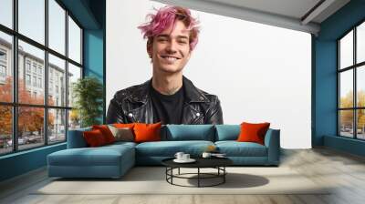 Portrait of handsome young pink haired man dressed in black leather trousers and green reglan smiles gladfully expresses positive emotions isolated on white background with blank space : Generative AI Wall mural