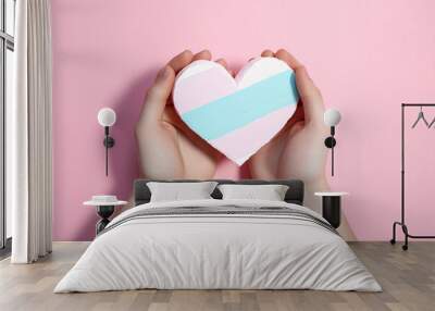 Two hands holding a paper heart with pride flag Wall mural