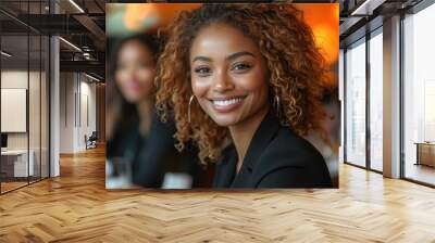 An African woman with curly hair smiles warmly at the camera in a restaurant filled with people enjoying their meals. Wall mural