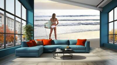 Young attractive surfer at the beach with surfboard Wall mural