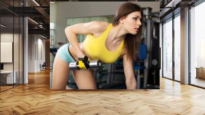 Young slim woman exercising in a gym Wall mural