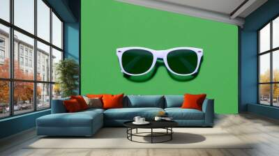 Light purple sunglasses top view  / flat lay on a green background with a centre composition Wall mural