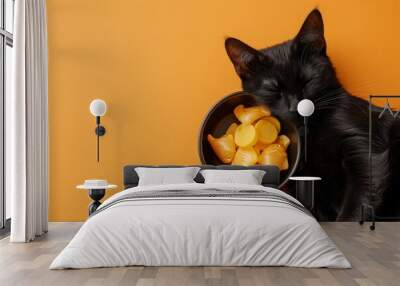 Black cat sleeping beside a bowl of goldfish crackers on orange background Wall mural