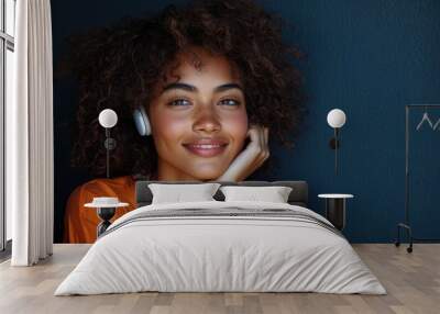 Cinematic fashion-inspired portrait of a happy young woman with curly hair and a bright smile against a deep blue background Wall mural