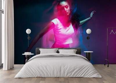 Colourful portrait of young mixed race girl dancing in studio. Long exposure. Colored neon light. Wall mural