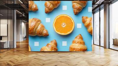 Creative pattern of croissants and orange slices on a blue background for a vibrant food arrangement Wall mural