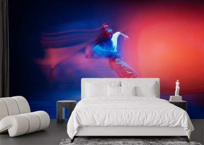 Dancing female standing on tiptoe in colourful neon studio light. Long exposure. Contemporary hip hop dance Wall mural