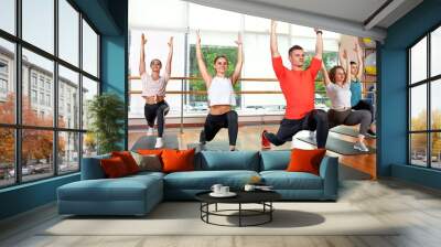 Group of young sporty attractive people practicing yoga lesson with instructor, standing together in exercise, working out, full length, studio background, close up Wall mural