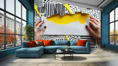 Hands tearing a white sheet of paper surrounded by abstract black and yellow artistic splashes Wall mural