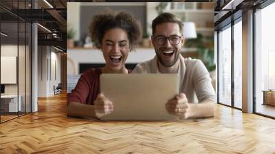 Happy couple celebrating success while watching something exciting on a tablet at home Wall mural