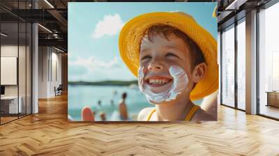 Joyful child with sun cream on face wearing a yellow hat at the beach Wall mural