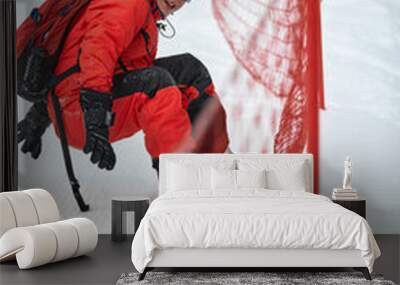 Male snowboarder in a red suit rides on the snowy hill with snowboard, Skiing and snowboarding concept Wall mural