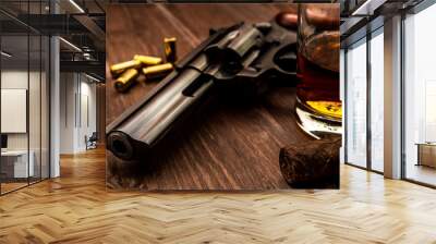 Glass of whiskey with revolver and cuban cigar on the wooden table Wall mural