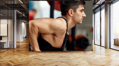 Strong muscular man doing push-ups on uneven bars in gym. Workout lifestyle concept. Wall mural