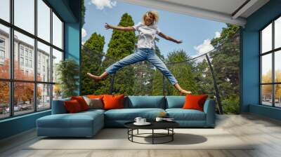 Young Female Jumping On Trampoline Outdoors Wall mural