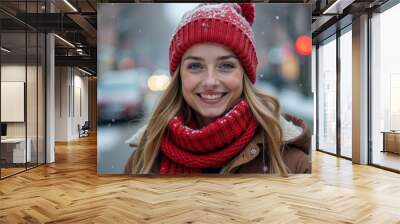 Beautiful happy young woman in red knitted hat and scarf against winter city background. Banner. Wall mural