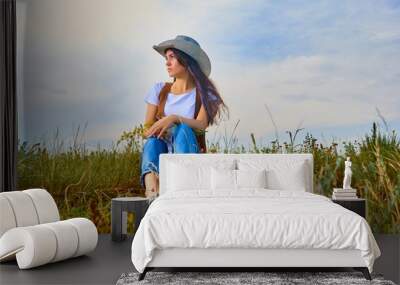 Girl in cowboy dress standing back on the top of Caucasus mountain with a scenery view to sunset at green valley. Female travel nature concept. Wall mural