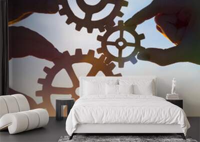 Four hands of businessmen collect gear from the gears of the details of puzzles. against the background of sunlight. The concept of a business idea. Teamwork. strategy, cooperation. Close-up Wall mural