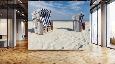 Two roofed wicker beach chairs at the coastline of the German island Norderney in front of the ocean. Wide angle view Wall mural