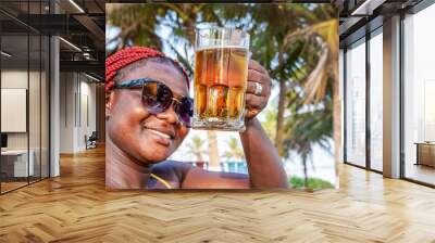 African happy woman drinking a beer out at a beach bar in Accra Ghana West Africa Wall mural