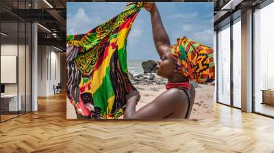 Ghana woman on the beautiful beach of Axim, located in Ghana West Africa. Headdress in traditional colors from Africa. Wall mural