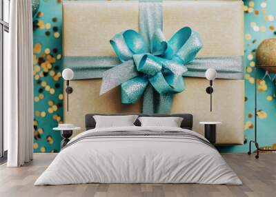 gift in the foreground in a brown box with a shiny blue ribbon on a blue background with golden glitter Wall mural