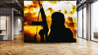 Muslim militant with rifle in the desert on sunset with AK rifle Wall mural