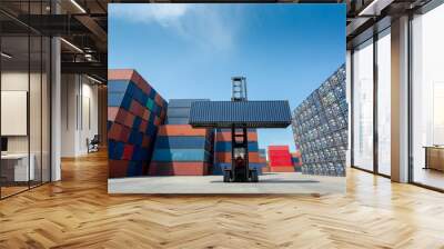 Forklift truck lifting cargo container in shipping yard or dock yard against blue sky with cargo container stack in background for transportation import,export and logistic industrial concept Wall mural