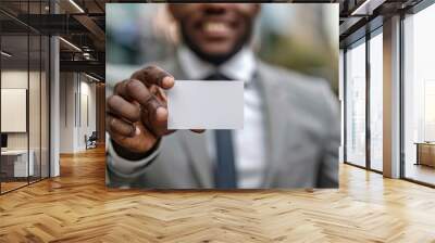 A close-up shot of an African American businessman's hand holding out his business card. Wall mural