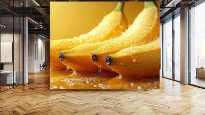 Close-up of fresh ripe yellow bananas with water droplets on a yellow background. Wall mural