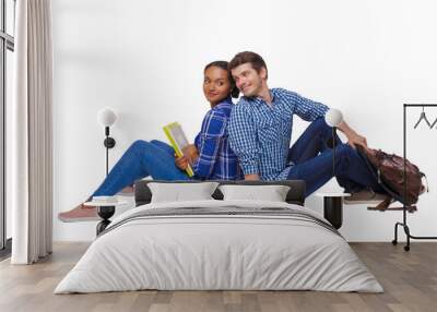 Side view of a couple of students who are sitting on the floor with their backs. Wall mural