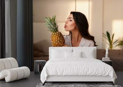 beautiful woman at home, eats a pineapple Wall mural