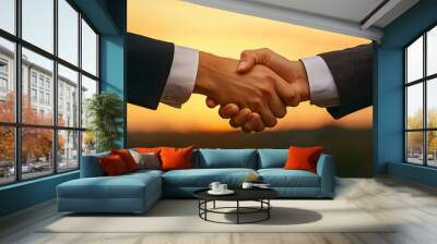 A close up of two entrepreneurs shaking hands against sunset backdrop, symbolizing partnership and agreement. Wall mural