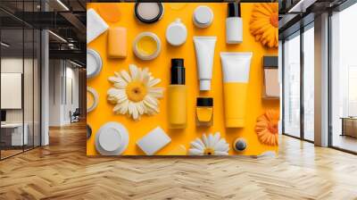 A flat lay of various beauty products in shades of yellow and white, including bottles with black caps, tubes with orange labels,  Wall mural